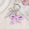 Detail van zoete paarse hars strik sleutelhanger met zilveren vlinder hanger op pluche - Paars