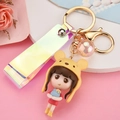 Cartoon girl keychain with yellow animal hat and pink sequin ball on a colorful strap - Pink Yellow