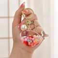 Luminous whale liquid sand keychain with golden metal ring and white pearl charm - Jelly Bean Red