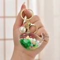 Creative whale keychain with green sequins and white pearl charm held by a hand - Light Gold Buckle + Luminous Fish + Bell + Pearl / Jelly Bean Green