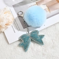 Dettaglio del portachiavi con pompon in ecopelliccia azzurra e fiocco di strass su peluche - Portachiavi+Fiocco+Pompon / Celeste