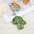 Detail shot of sparkling rhinestone mushroom keychain with blue tassel and silver bell - Tassel Style / Green