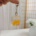 Glow-in-the-dark acrylic liquid sand keychain with yellow pearls and pink flowers - Lobster Clasp + Luminous Cube / Orange