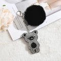 Detail view of a black faux fur pompom keychain with a sparkling rhinestone bear pendant - Black with White Rhinestones