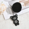 Detail of a black plush fur ball keychain with a rhinestone bear pendant and silver chain - Black