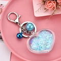 Detail of blue acrylic heart keychain with liquid glitter, metal bell and lobster clasp - Light Blue