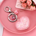 Vue détaillée du porte-clés cœur en acrylique avec paillettes roses et petite clochette - Rose