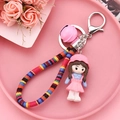 Close-up of cute resin doll keychain with colorful braided rope and pink metal bell - Pink