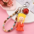 Close-up of a cartoon monk keychain with red robe, woven strap and metal bell accessory - Tang Sanzang (Orange)