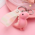 Close-up of pink flocked dinosaur keychain with matching striped strap and lace background - Pink