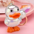 Macro shot of colorful iridescent 3D duck keychain with rose gold ring on pink background - Light Blue