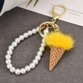 Close-up of creative ice cream keychain with yellow faux fur and pearl handle detail - Yellow