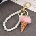 Close-up of pink faux fur ice cream keychain with white pearl chain and golden clasp - Pink