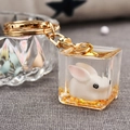 Détail macro d'un porte-clés lapin mignon dans un cube en résine avec paillettes d'or - Doré