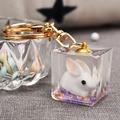 Macro d'un lapin 3D dans un cube en résine avec paillettes dorées pour porte-clés - Violet