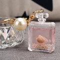 Detalle de llavero con forma de frasco de perfume, líquido rosa, concha y gran perla blanca - Rosa