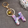 Detail of resin letter H keychain with colorful stones, gold bell and lobster clasp - Letter H
