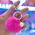 Detailed view of fuchsia faux rabbit fur keychain with gold ring and pearl charm decoration - Rose Red