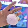 Close-up of pink faux rabbit fur pom pom keychain with large white pearl and gold hardware - Pink