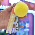 Detail van gele pluche bal sleutelhanger met nagelknipper en siliconen polsbandje - Geel