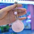 Detailed shot of pink faux fur pompom keychain with gold heart clasp and sequin bottle - Pink