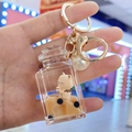 Dettaglio del portachiavi a tazza di tè con orsetto marrone e grande perla bianca - Bottiglia Quadrata