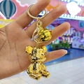 Gros plan détaillé d'un porte-clés ours en métal doré poli avec clochette et mousqueton - Boucle en Or Clair + Ours + Cloche / Doré