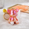 Close-up of a gradient pink bear keychain with golden bell and orange wrist strap - Strap Buckle + Bear + Bell / Orange