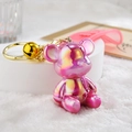 Detailed close-up of a laser gradient bear keychain with golden bell and pink silicone strap - Strap Buckle + Bear + Bell / Pink