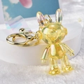 Detail of yellow iridescent space bunny keychain with mechanical design and golden ring - Lemon Yellow
