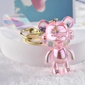 Makro-Detail eines rosa schillernden Bären-Schlüsselanhängers mit Kopfhörern und Goldring - Rosa