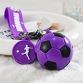Dettaglio macro del portachiavi calcio viola con cinturino in silicone e gancio nero - Stile Cordino / Viola