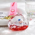 Detail of liquid cloud keychain featuring a white sheep, red sand, and pink wrist strap - Red