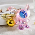 Makroaufnahme: Rosa Acryl-Hase Schlüsselanhänger mit goldener Glocke und Astronautenmaske - Hellgoldene Schnalle + Sternenhimmel Hase Glocke / Rosa