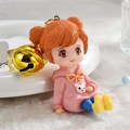 Close-up of pink hoodie girl keychain with orange buns and shiny gold bell charm - Yellow-Pink Girl