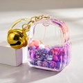 Détail du porte-clés sac à dos avec liquide violet pailleté et clochette dorée - Violet
