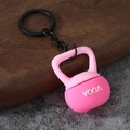 Close-up of a pink silicone kettlebell keychain with white YOGA lettering on a wood surface - Yoga Kettlebell-Pink