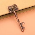 Macro detail of vintage bronze key bottle opener with intricate hollow decorative bead head - Antique Red