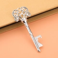 Close-up of vintage silver key bottle opener with hollow decorative pattern for weddings - Silver