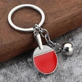 Metal table tennis paddle keychain with red rubber and silver ball on wooden background - Table Tennis