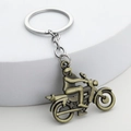 Vintage-Motorrad-Schlüsselanhänger aus Bronze auf einem weißen Steinsockel - Bronze