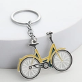 Sleek bicycle metal keychain with vibrant yellow lacquer finish on a white modern pedestal - Yellow