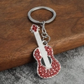 Polished silver guitar keychain with red rhinestones on a rustic wooden surface - Red Rhinestone
