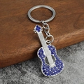 Dettaglio del portachiavi a chitarra argento con strass blu su sfondo di legno - Strass Blu