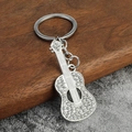 Dettaglio di un portachiavi a forma di chitarra d'argento con strass luccicanti - Trasparente