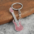 Porte-clés guitare créatif en argent avec strass roses brillants sur fond de bois naturel - Strass Rose