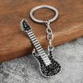 Porte-clés guitare argenté brillant avec strass noirs sur un fond en bois rustique - Zircon Noir