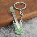 Close-up of a silver guitar keychain with sparkling green rhinestones and metal ring - Green Rhinestone