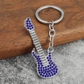 Gros plan d'un porte-clés guitare électrique argenté avec des cristaux strass bleus - Strass Bleu
