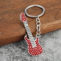 Macro d'un porte-clés guitare argenté avec strass rouges étincelants et texture métallique - Strass Rouge